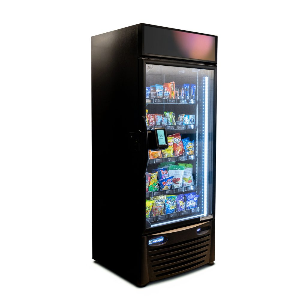 A professional using tap-to-pay on a modern, AI-powered smart fridge vending machine in a Denver corporate breakroom, installed by Viola Vending.
