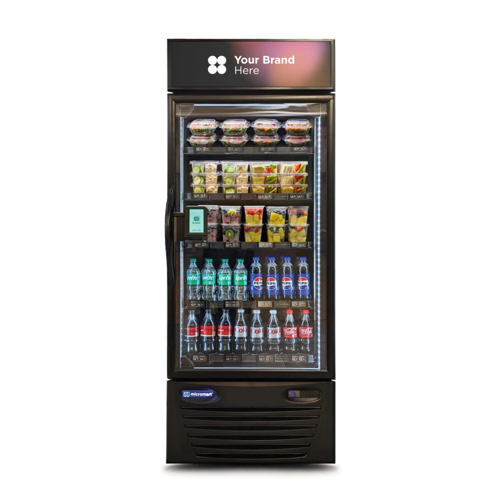 A brightly lit smart fridge inside a Denver corporate micro-market, stocked with healthy snacks, fresh artisan salads, and premium cold brew beverages.